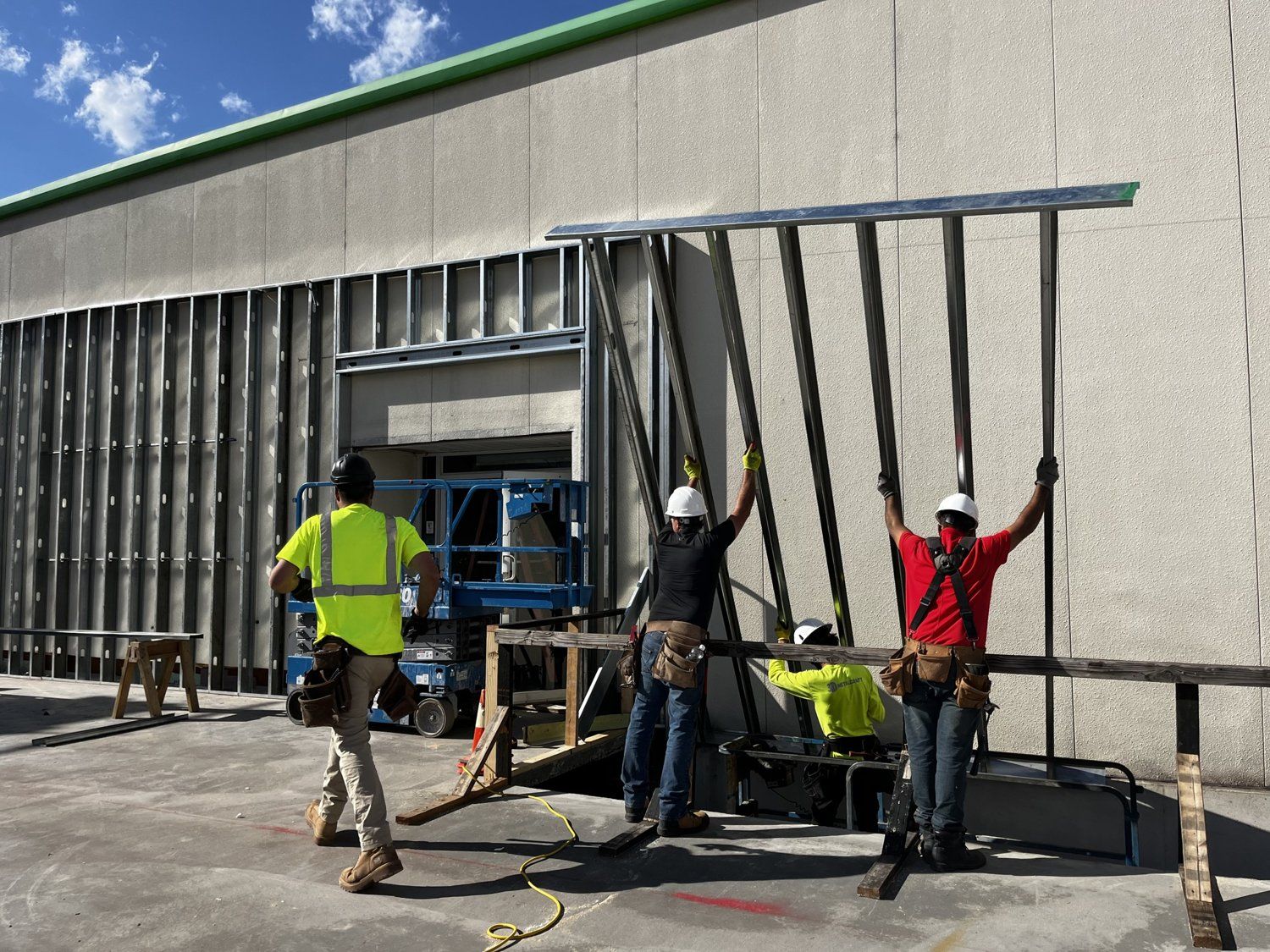 NYSIDI crew in hard hats and harnesses setting a steel-stud wall panel