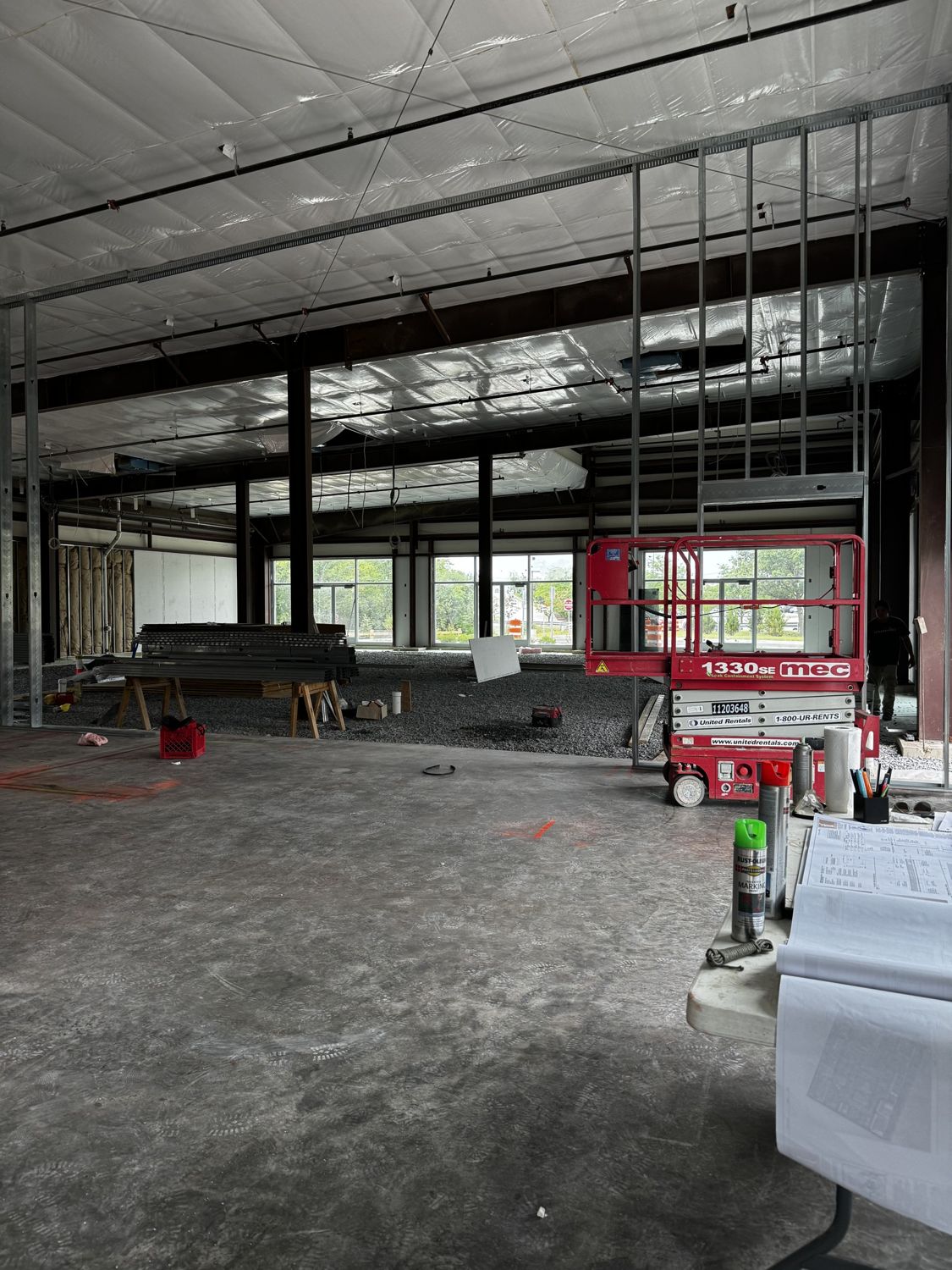 Open-plan commercial interior mid-buildout — steel framing and lift