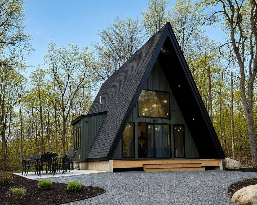 Completed A-frame custom home at dusk — landscaped grounds and glowing window wall