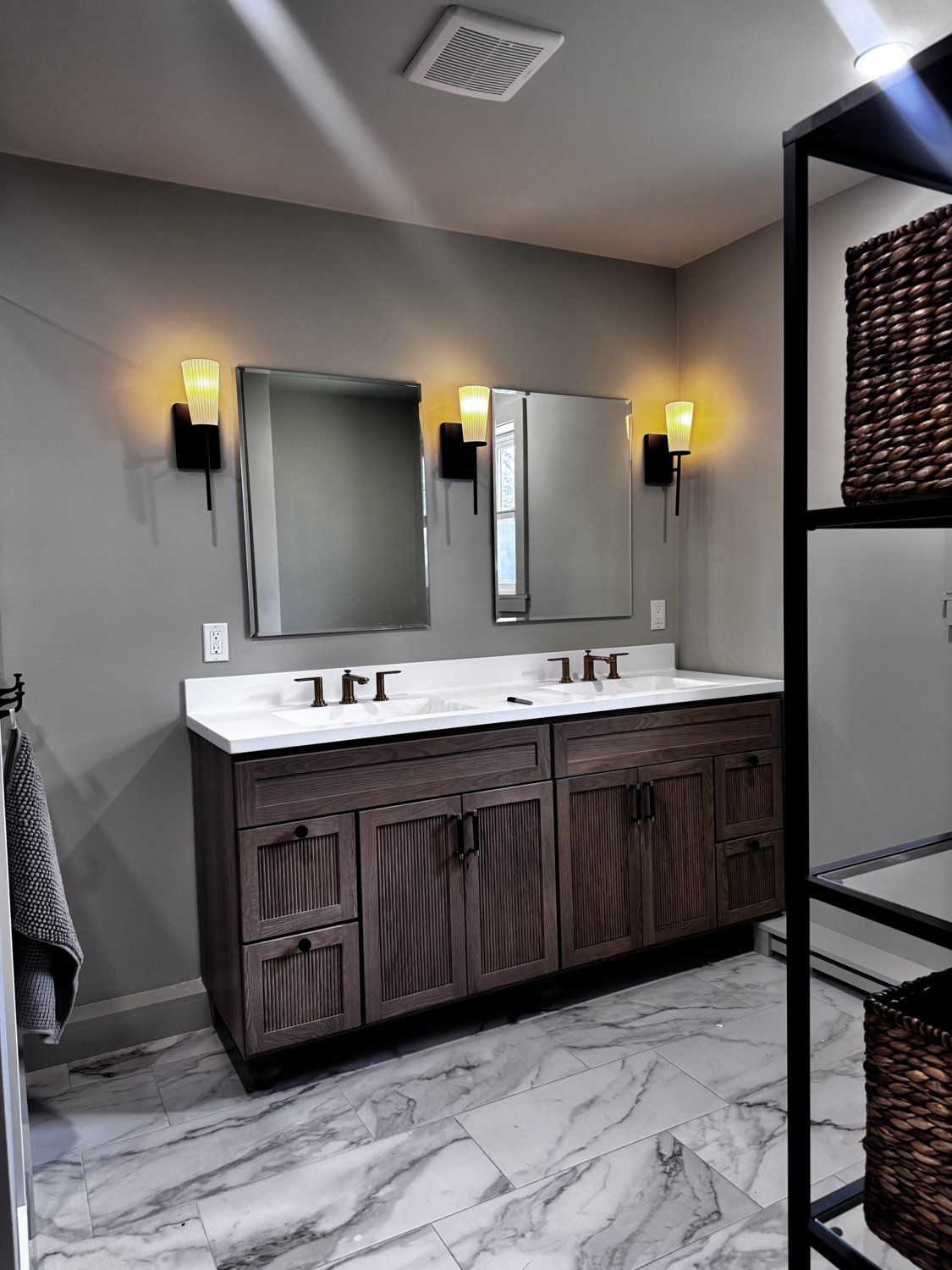 Finished primary bathroom — double vanity, marble floor, modern sconces