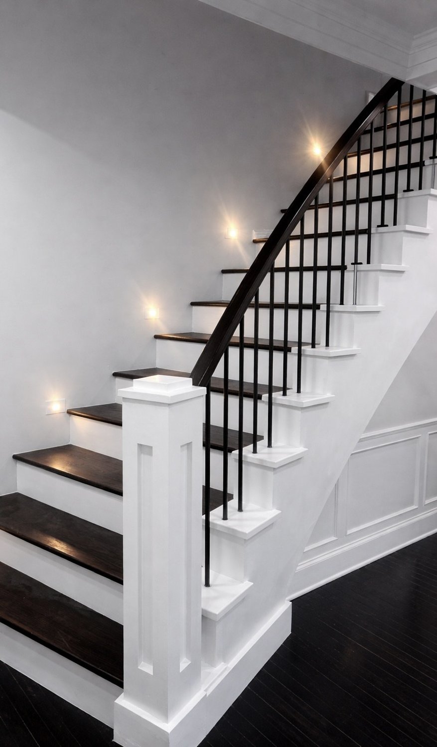 Finished open staircase — dark treads, black railing on white walls
