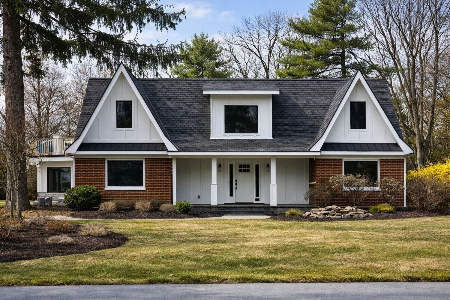 Finished custom home exterior — brick and board-and-batten facade, twin gables, covered entry, landscaped grounds